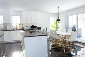 a kitchen with white cabinets and a table and chairs at Cozy Cottage, The Getaway in Quebec in Brownsburg