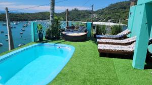 a swimming pool on a lawn with a view of the water at Marques Home in Porto Belo