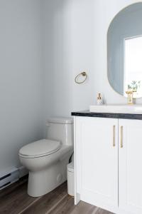 a white bathroom with a toilet and a sink at Cozy Cottage, The Getaway in Quebec in Brownsburg +19 photos