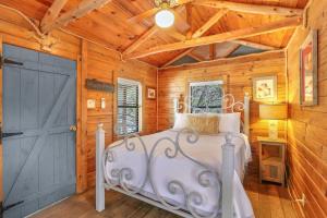 a bedroom with a white bed in a room with wooden walls at Cozy Cabin in Wimberley