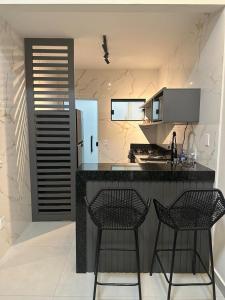 a kitchen with two chairs and a black counter top at Casa Condeixa in Cabo Frio