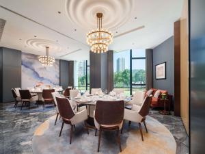 a dining room with a table and chairs and chandeliers at Pullman Chongqing Xiyue in Chongqing +149 photos