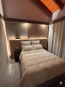 a bedroom with a large bed with white sheets and pillows at Cabaña julian in Villa Berna