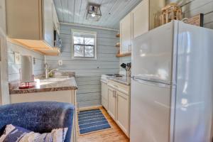 a kitchen with a white refrigerator and wooden cabinets at Creekside Cabins - The Texan in Wimberley