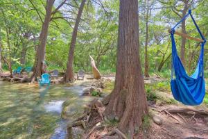 a hammock hanging from trees next to a river at Creekside Cabins - The Texan in Wimberley +4 photos