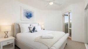 a white bedroom with a white bed and a window at Heart and Shoal in Shoal Bay