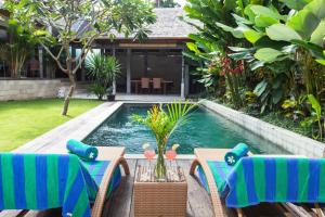a swimming pool with a table and chairs and a pool at Villa Liang by Nagisa Bali in Seminyak