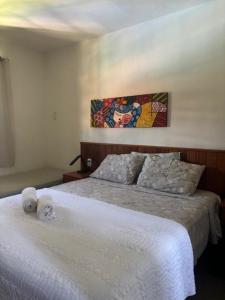 a bedroom with a white bed with two pillows at Cond Residencial Resort Pipa Chalés Triplex - Centro de Pipa in Pipa +26 photos