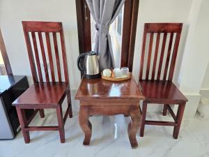 two wooden chairs and a table with a tea kettle on it at Villa ThreeD Xaydara in Luang Prabang