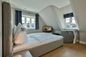 a bedroom with a bed and a tv and windows at Sand Beach in Rantum