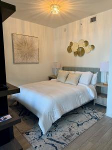 a bedroom with a large white bed and a chandelier at Azure Miami - Studio Apartment with Stunning City & Bay Views! in Miami
