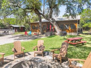 a group of chairs and a picnic table in front of a cabin at Wimberley Log Cabins Resort and Suites- The Oak Lodge in Wimberley