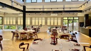 a restaurant with white tables and chairs and windows at Robyn's Nest Lakeside Resort in Merimbula