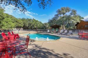 a patio with red chairs and a swimming pool at Wimberley Log Cabins Resort and Suites- Reunion Cabin in Wimberley