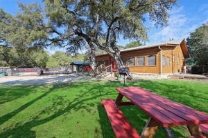 a picnic bench in front of a log cabin at Wimberley Log Cabins Resort and Suites- Reunion Cabin in Wimberley