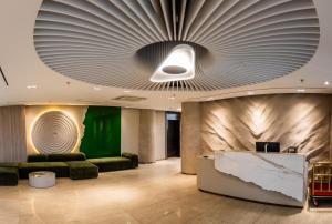 a lobby with a large ceiling with a green wall at Green gobi hotel in Dalandzadgad