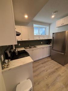 a kitchen with white cabinets and a stainless steel refrigerator at Hidden Gem in Airdrie