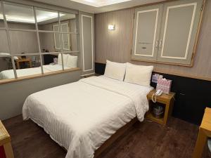 a bedroom with a large white bed and a mirror at Rosemari Hotel in Seoul