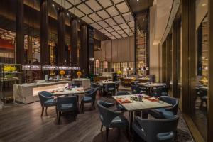 a restaurant with tables and chairs and a kitchen at JiuTai Hotel Hangzhou in Hangzhou
