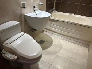 a bathroom with a toilet and a sink and a tub at Rosemari Hotel in Seoul +1 photo