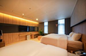 ein Schlafzimmer mit zwei Betten und einem Flachbildfernseher in der Unterkunft Naju Holius Hotel in Naju