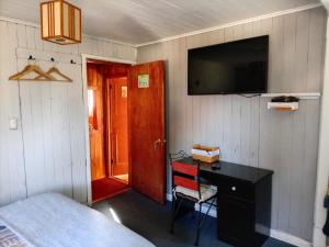 a bedroom with a desk and a television on the wall at Habitación Bosque Mar in Isla Negra