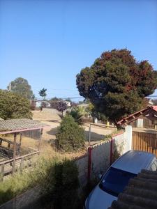 a car parked next to a fence with a tree at Habitación Bosque Mar in Isla Negra