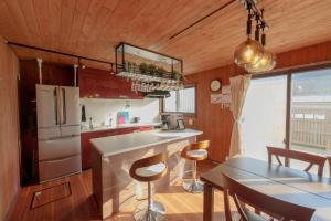 a kitchen with a refrigerator and a table with chairs at まるで映画館 本格シアター 寝室6部屋 大家族大集合 海まで徒歩すぐ ---オーシャニア一宮--- in Ichinomiya