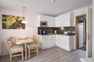 a kitchen with white cabinets and a table and chairs at Fewo Luv in Kühlungsborn +5 photos