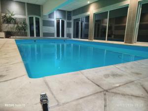 a swimming pool with blue water in a building at Gîte "fils et cotons" Piscine Intérieure chauffée à l'année et sauna in Celles-sur-Plaine