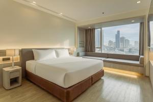 a bedroom with a large bed and a large window at Jasmine Grande Residence Suite Bangkok in Bangkok