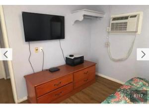a room with a dresser with a tv on a wall at El Muir Motel in Fresno