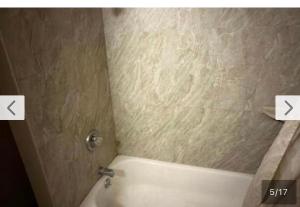 a bathroom with a tub and a shower with two arrowscodedlettersletters at El Muir Motel in Fresno