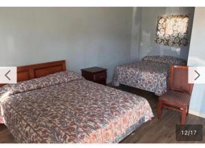 a hotel room with two beds and a chair at El Muir Motel in Fresno