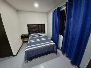 a small bedroom with a bed with blue curtains at Casa Rayon Oaxaca in Oaxaca City +4 photos
