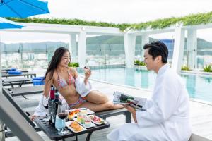 a man and a woman sitting on a table with food at Odin Hotel Quy Nhon in Quy Nhon