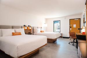 a hotel room with two beds and a desk at Boundary Hotel By Terra Vi, Durango in Durango