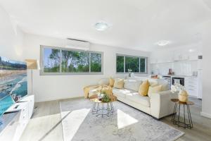 a white living room with a white couch and a kitchen at Collaroy 3Br Beach Home with Large Pool Ground Floor in Collaroy