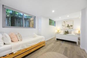 a white bedroom with a bed and a window at Collaroy 3Br Beach Home with Large Pool Ground Floor in Collaroy +25 photos