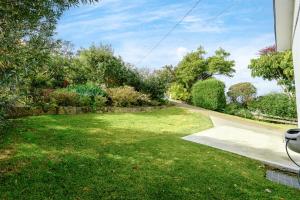 a yard with green grass and a driveway at Collaroy 3Br Beach Home with Large Pool Ground Floor in Collaroy