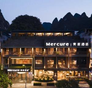 an exterior view of a hotel with mountains in the background at Mercure Guilin Yangshuo Xingping in Guilin
