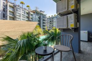 a balcony with a chair and a table and some palm trees at 2BR Family Condo with a Pool View - CTG P205 in Kamala Beach