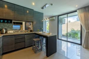 a kitchen with wooden cabinets and a large window at 2BR Family Condo with a Pool View - CTG P205 in Kamala Beach