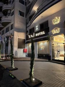 a hotel with two palm trees in front of a building at TAJ Hotel in Aqaba