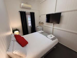 a bedroom with a white bed with red pillows on it at Hotel Metropole Proserpine in Proserpine