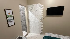 a living room with a brick wall and a flat screen tv at Suíte aconchegante 2 in Nova Mutum