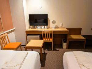 a hotel room with a desk with a television at Smile Hotel Sugamo in Tokyo