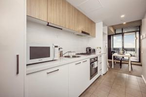 a white kitchen with a sink and a microwave at Two Bedroom Unit in Central Adelaide in Adelaide