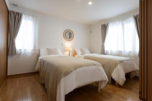 two beds in a white room with windows at Sa one ko Matsumoto Entire house Free parking 2cars in Matsumoto