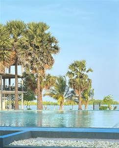 a swimming pool with palm trees and a building at Saachi Lagoon Resort in Kalpitiya